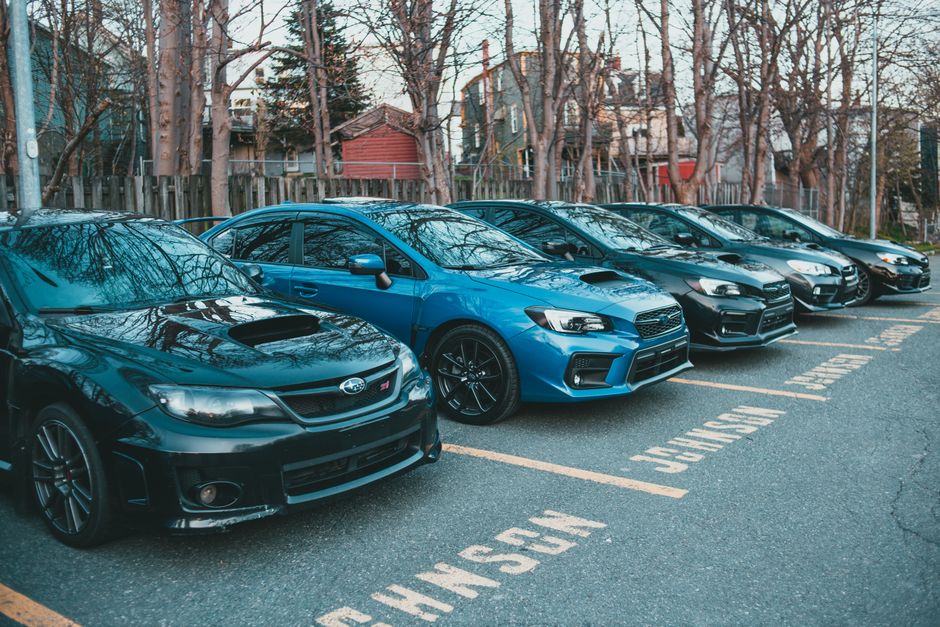 Multiple Subaru cars parked in an outdoor lot lined with trees
