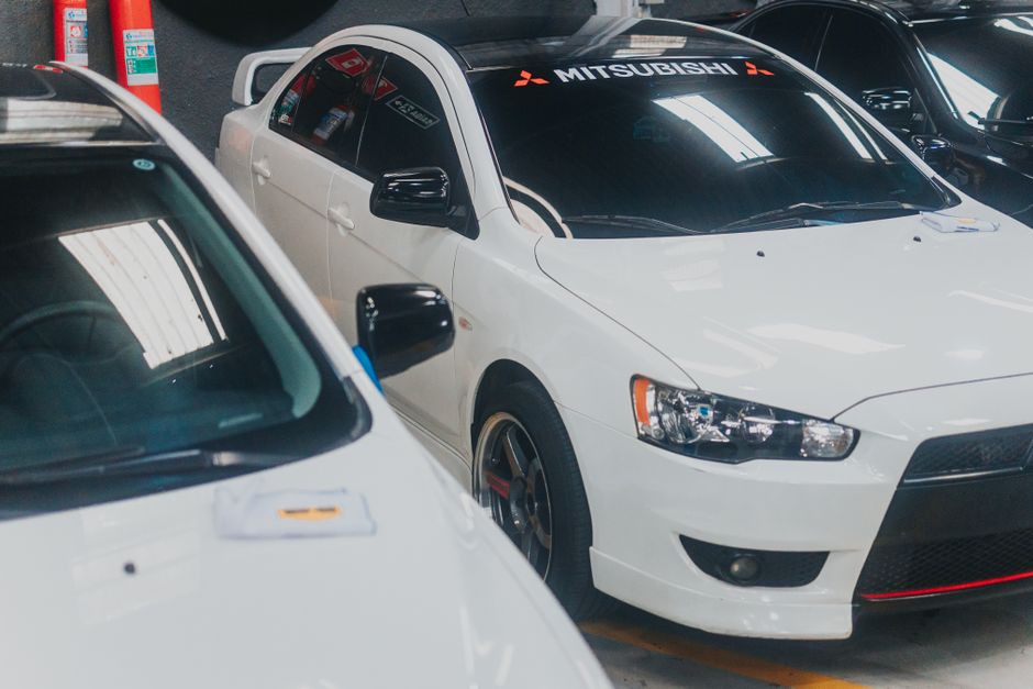 Close-up of a white Mitsubishi Lancer with decals in a garage setting
