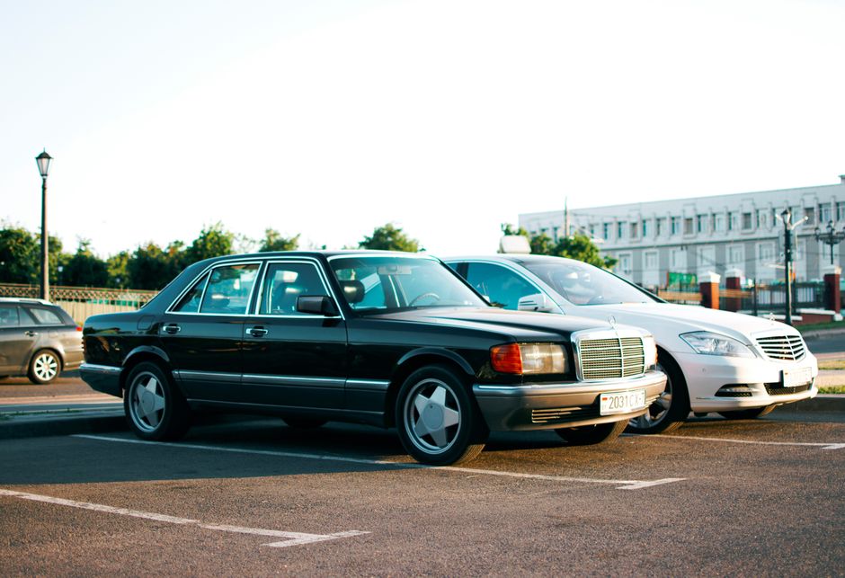 Two classic sedans parked in an urban parking lot on a sunny day