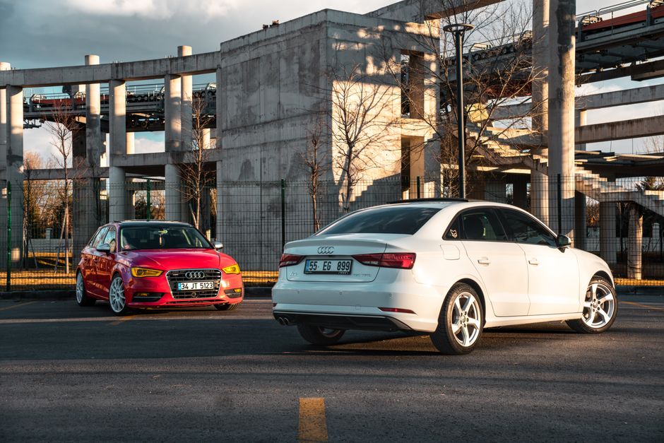 White and red Audi cars parked against industrial architecture outdoors