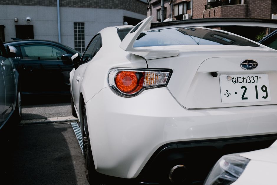 A stylish white Subaru BRZ parked in a city lot, showcasing its sporty rear design